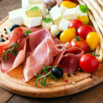 Tabla de aperitivos con jamón, queso, tomates cherry y grissini
